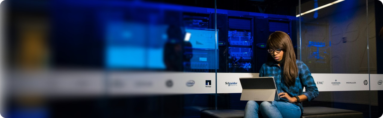 Analyst working on a tablet beside a server room